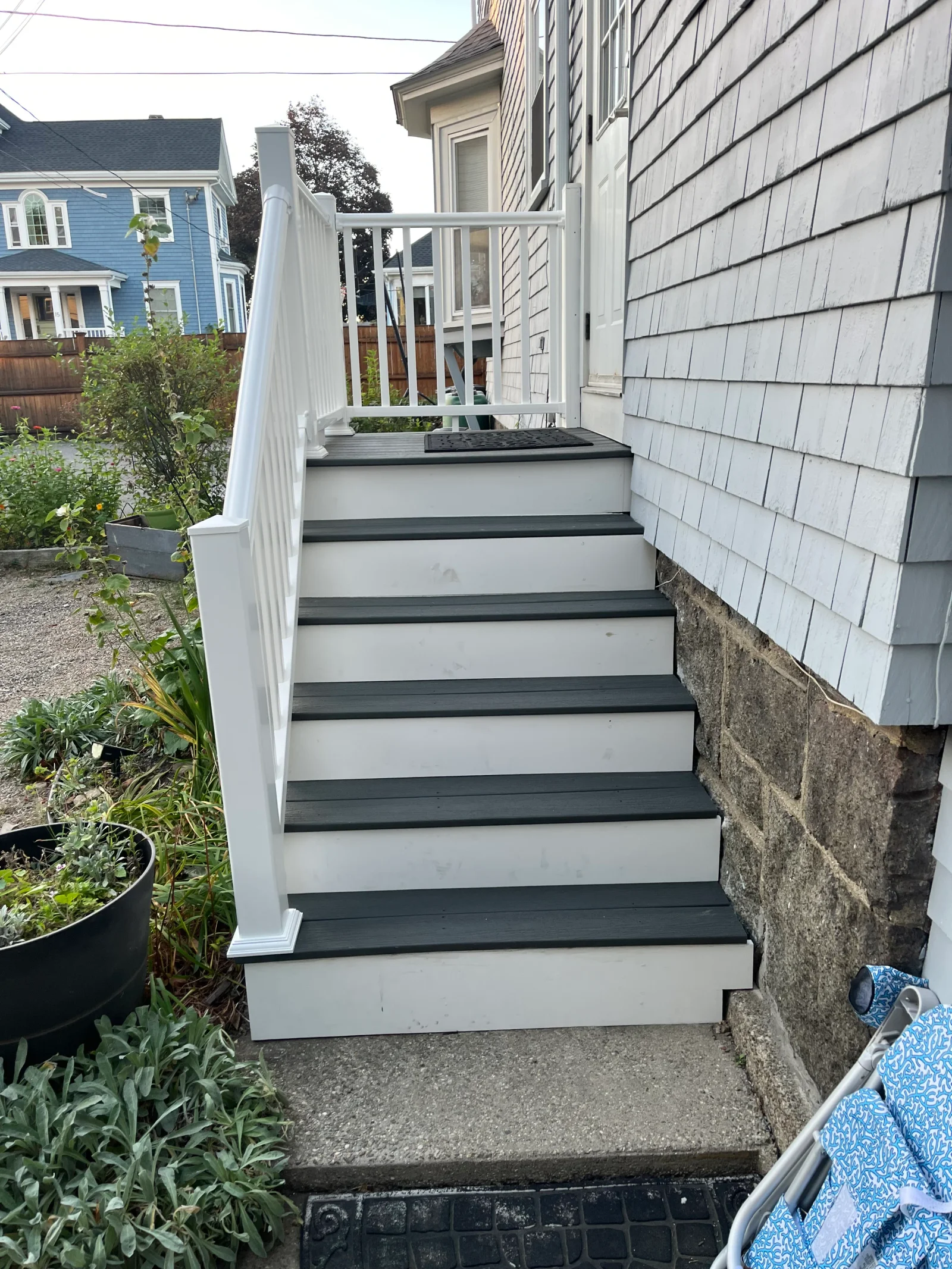 Gray composite stair treads with white risers and white vinyl railing with square balusters leading to a landing