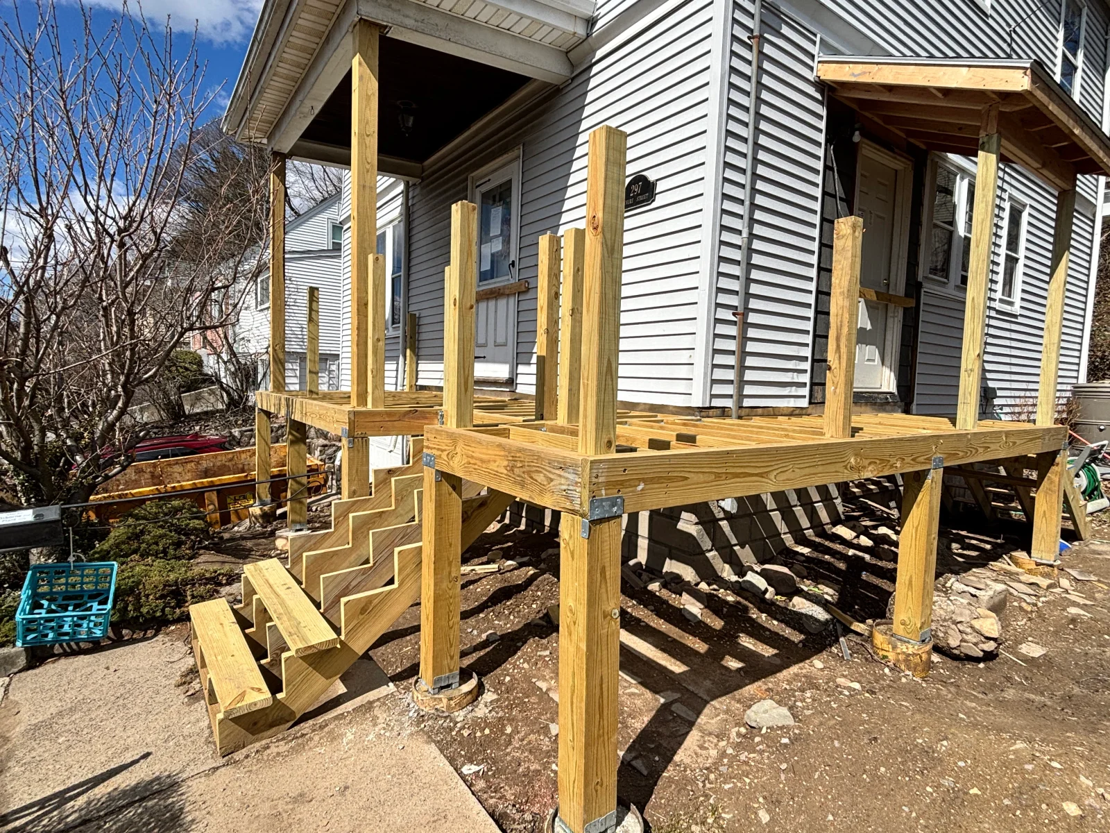 Pressure-treated wood deck framing with posts, beams, joists, and stepped stair stringers under construction